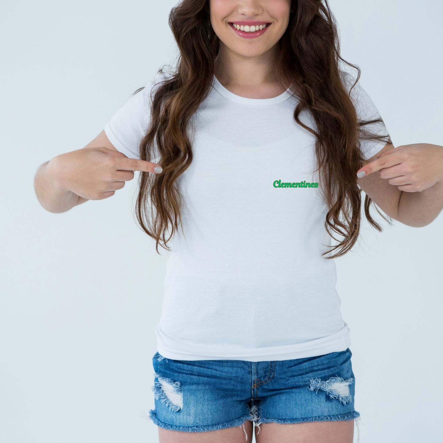 Person wearing a white t-shirt with a green logo, pointing at it on a plain background
