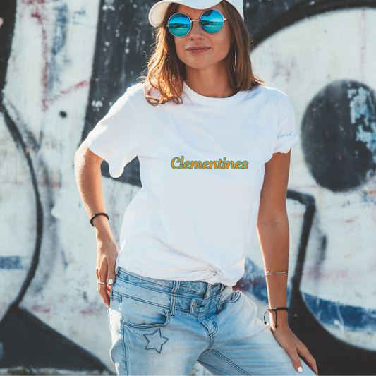 Woman wearing a white t-shirt with 'Clementines' text and blue jeans in front of a graffiti wall.