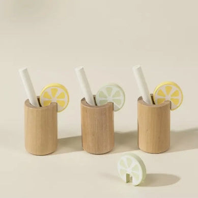 Three wooden cups with lemon slices and straws on a beige background