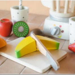 Wooden toy fruits and a cutting board on a tiled surface