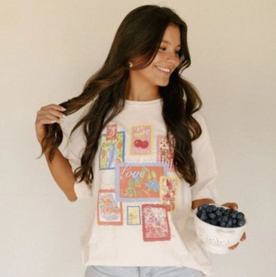 Woman wearing a colorful graphic sweatshirt holding a bowl of berries against a plain background