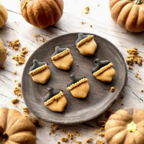 Acorn-shaped cookies on a plate with pumpkins around