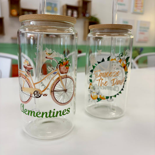 Two glass jars with bicycle and fruit designs on a white surface.