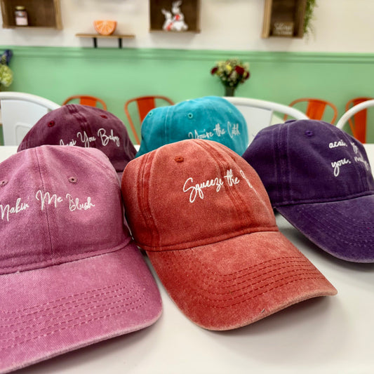 baseball caps in different colors with embroidered text on a table.