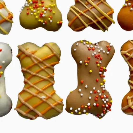 Dog treats shaped like bones with various toppings on a white background