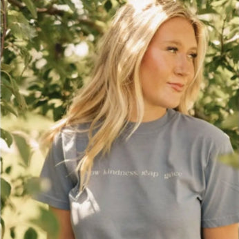 Woman wearing a gray t-shirt with text in an outdoor setting