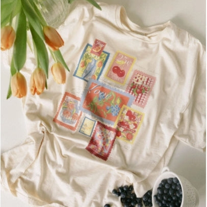 White t-shirt with colorful graphic design on a white surface with tulips and berries.