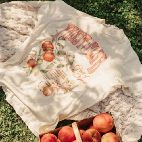 White shirt with peach design and text on grass