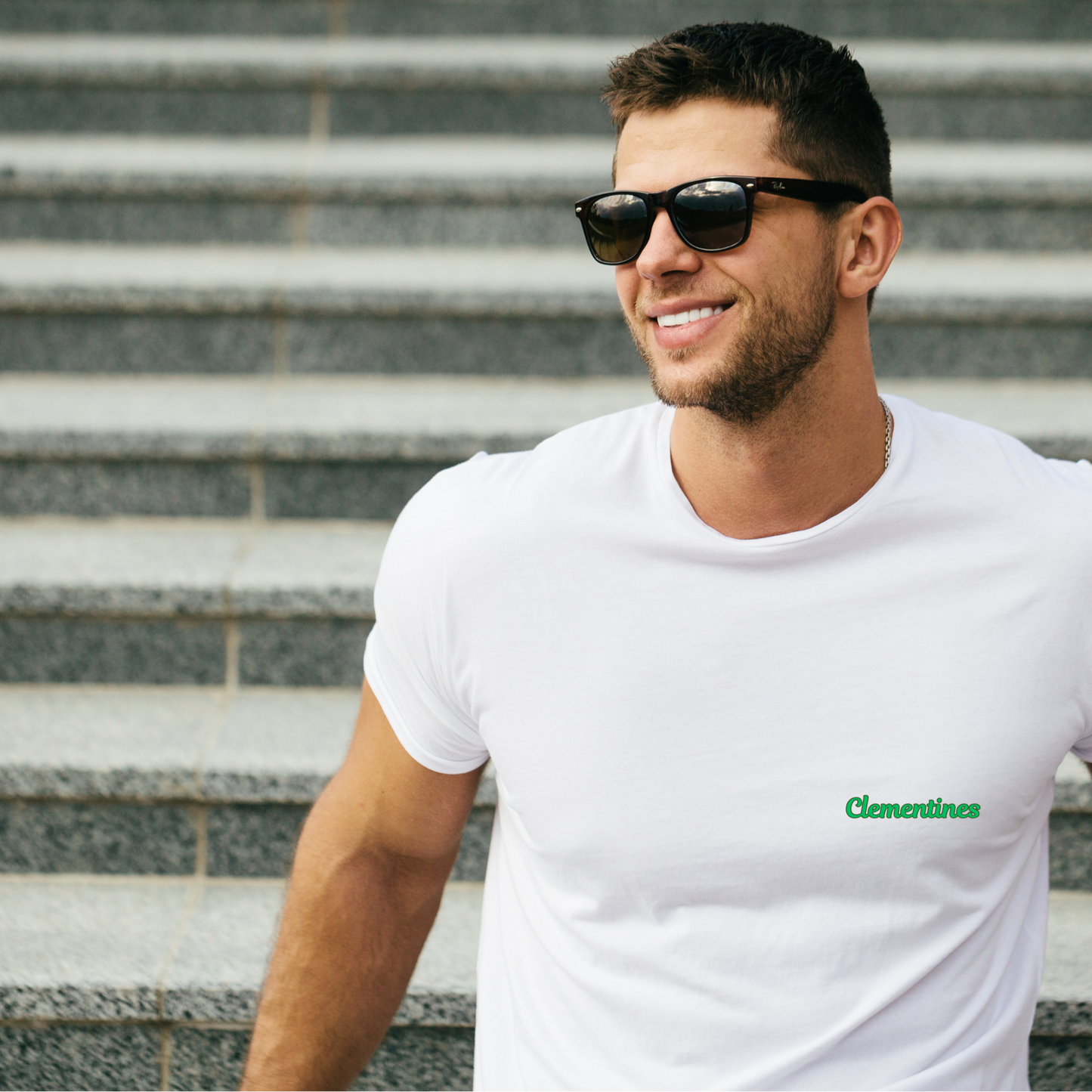 Man wearing sunglasses and a white t-shirt with a logo on steps