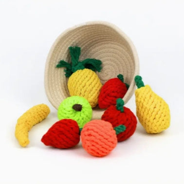 Knitted fruit toys including a pineapple, strawberry, banana, and pear on a white background.