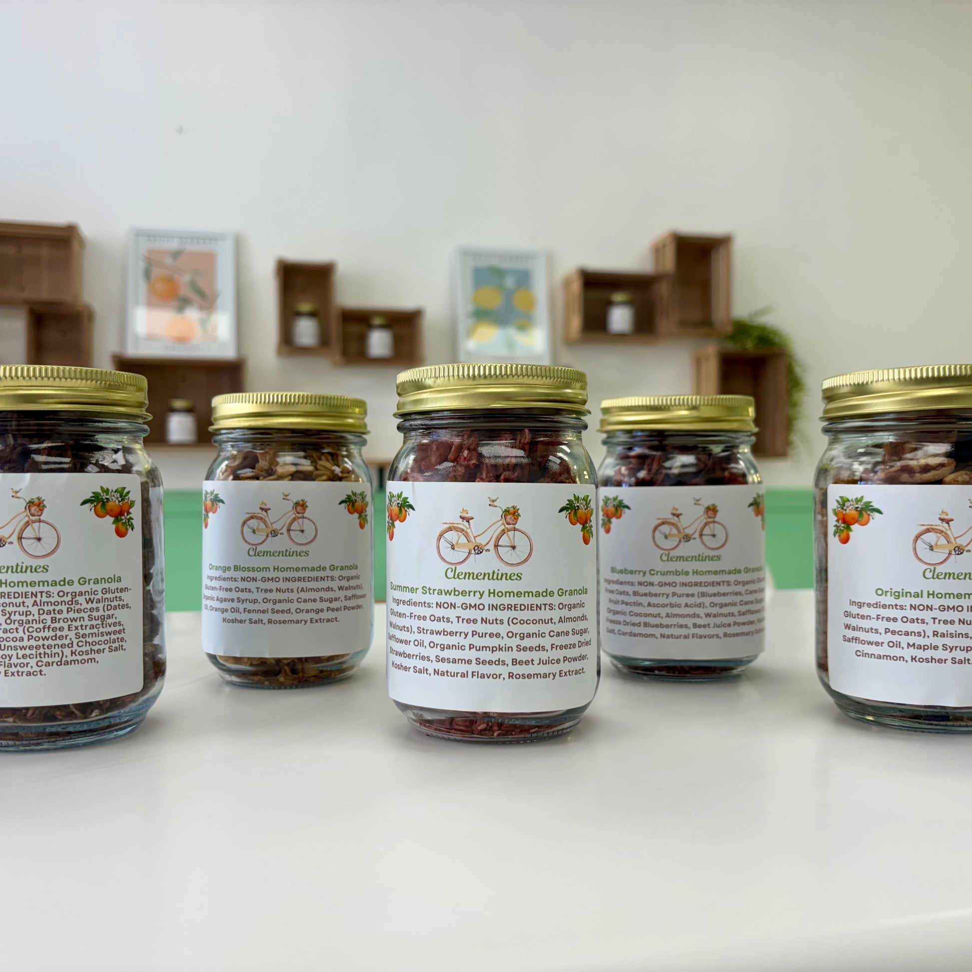 Five jars with labels on a white surface, with a blurred indoor background.