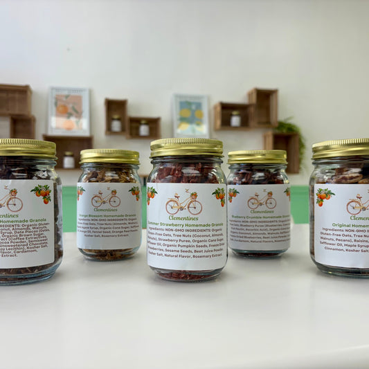 Five jars with labels on a white surface, with a blurred indoor background.