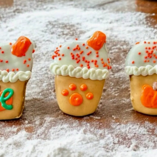 Decorative cookies shaped like ice cream cones with orange and green accents on a wooden surface.