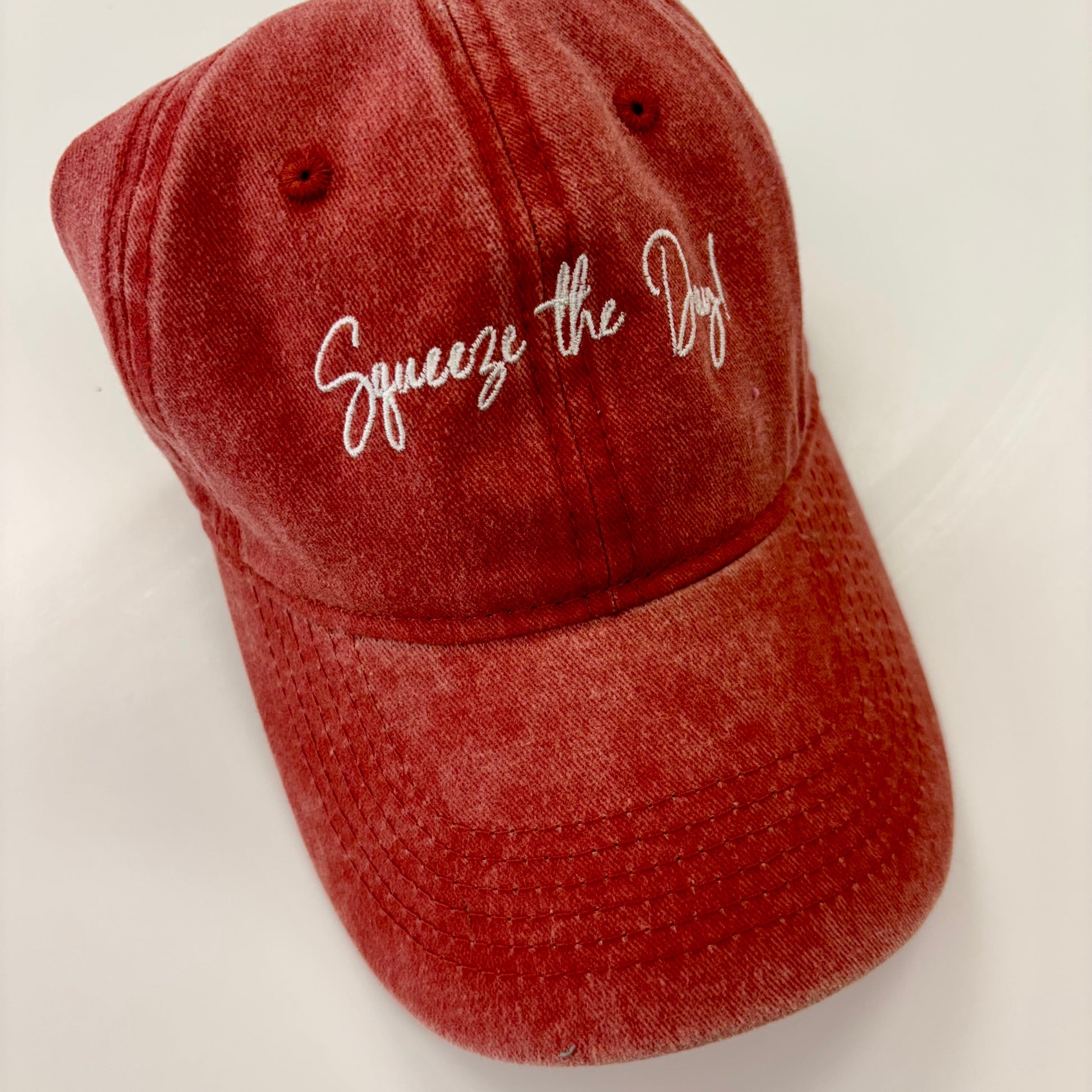Red cap with 'Squeeze the Dog' text on a white background