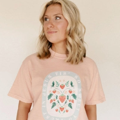 Woman wearing a pink t-shirt with a floral design on a beige background