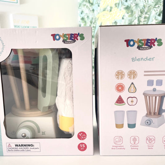 Two toy blenders in their packaging on a white surface with a blurred background.
