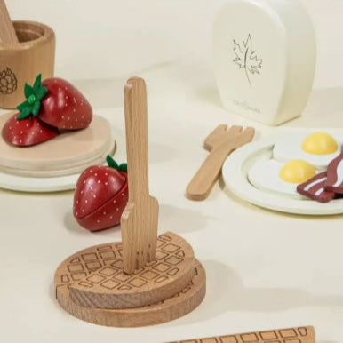 Wooden toy kitchen set with fruits, utensils, and a plate on a light background