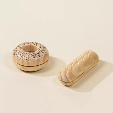 Wooden donut-shaped container with sprinkles next to a wooden loaf of bread on a beige background