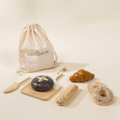 Set of toy bread and pastries with a CoCo Village drawstring bag on a light background