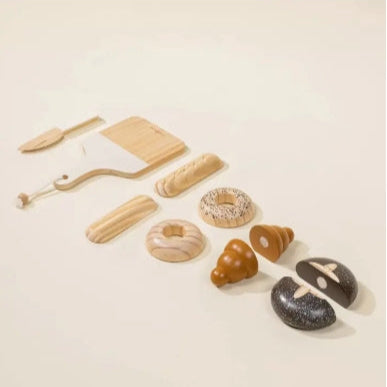 Set of toy bread and baking tools on a beige background