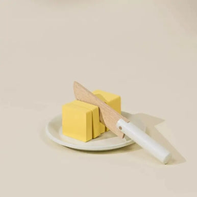Two blocks of butter on a white plate with a knife on a beige background