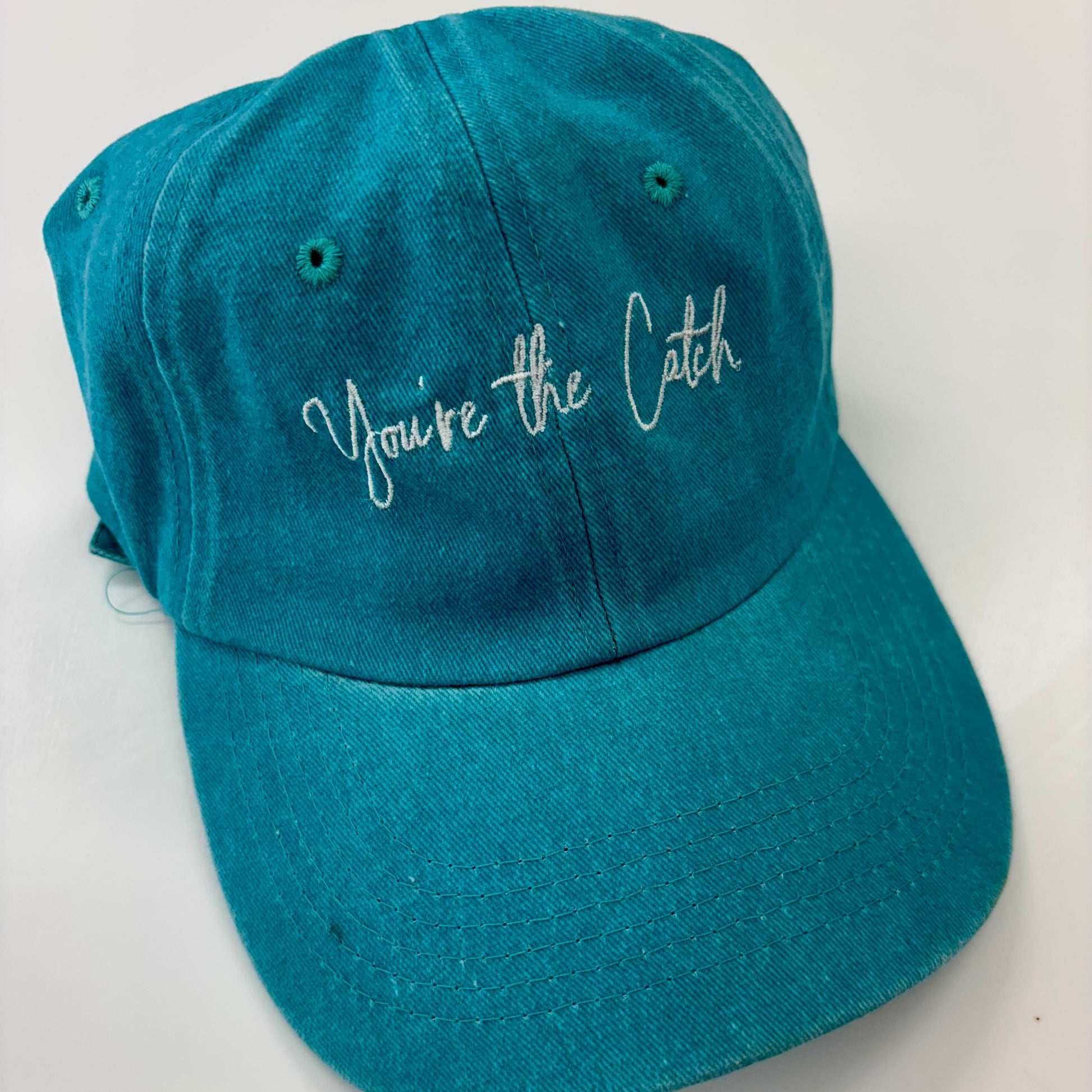 Teal cap with 'You're the Catch' text on a white background