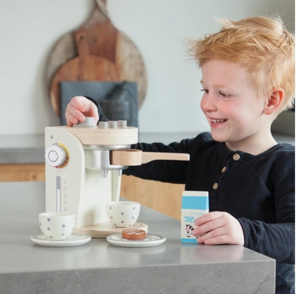 Child playing with a toy kitchen set on a table