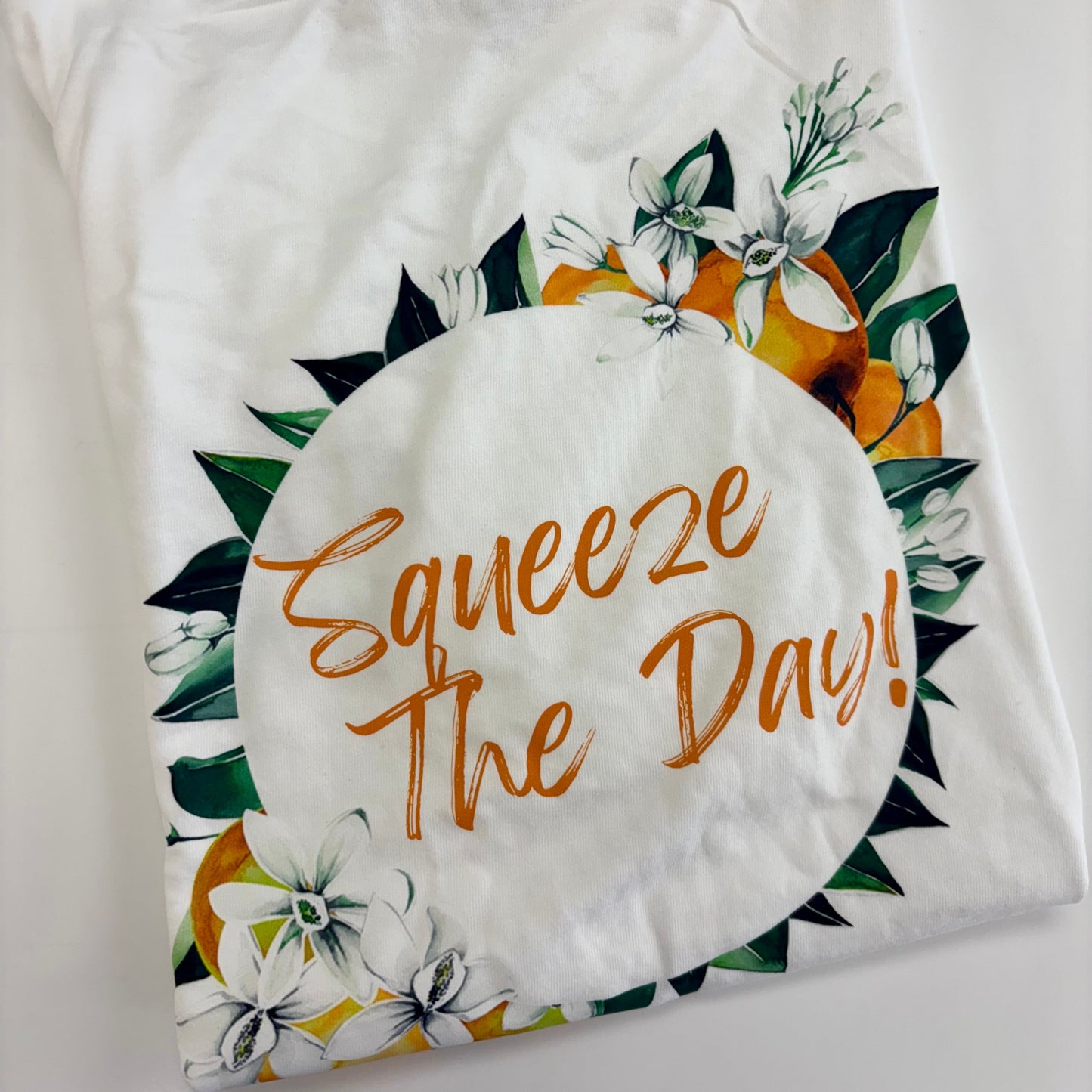 White pillow with floral design and 'Squeeze The Day!' text on a white background