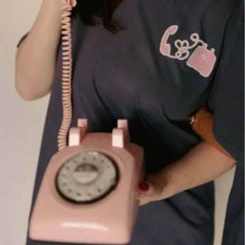 Person holding a pink vintage-style telephone-shaped bag