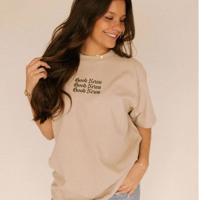 Woman wearing a beige t-shirt with text, standing against a plain background