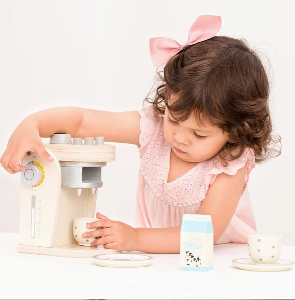 Child playing with a toy kitchen set on a white background