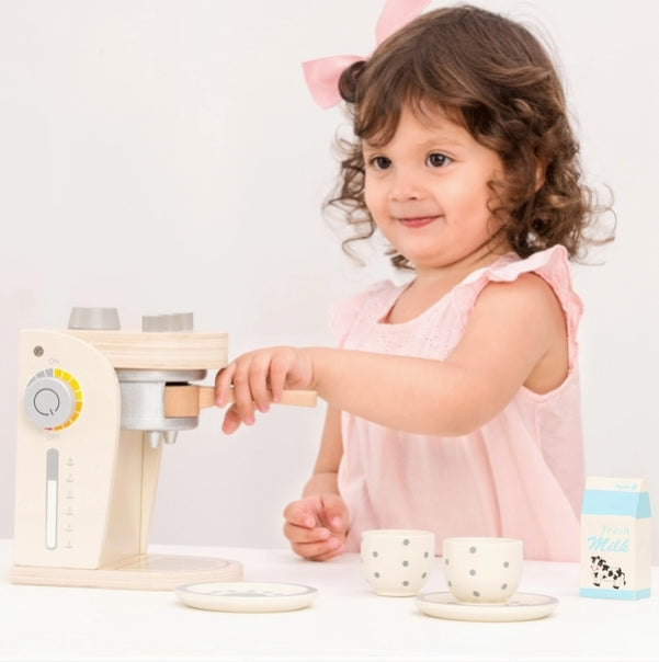 Child playing with a wooden toy kitchen set on a white background
