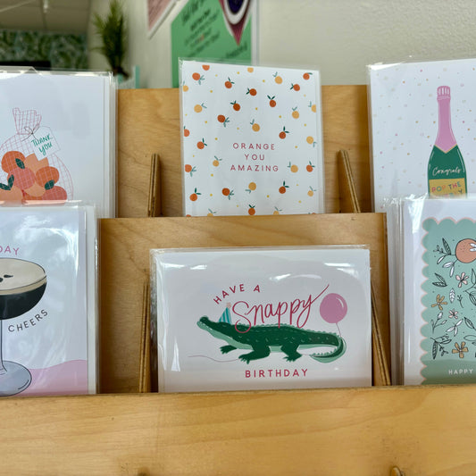 Collection of greeting cards on a wooden surface with various designs.