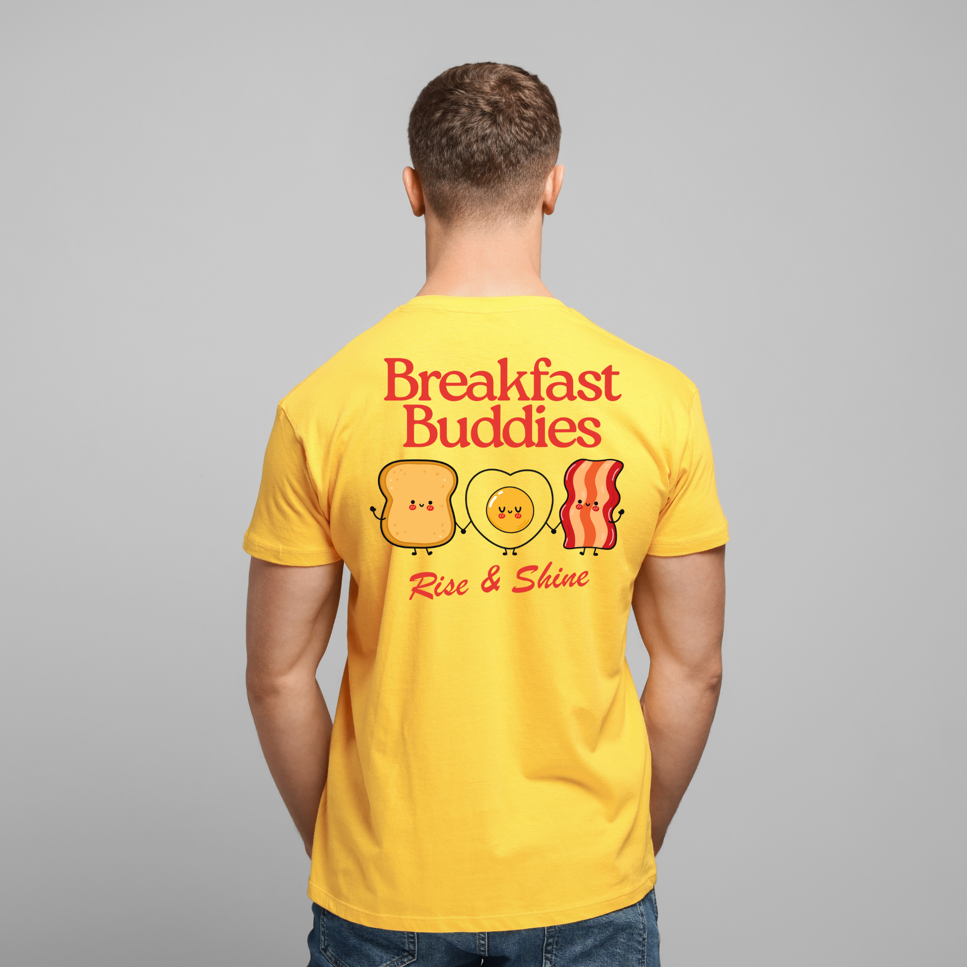 Man wearing a yellow t-shirt with 'Breakfast Buddies' design on the back against a gray background