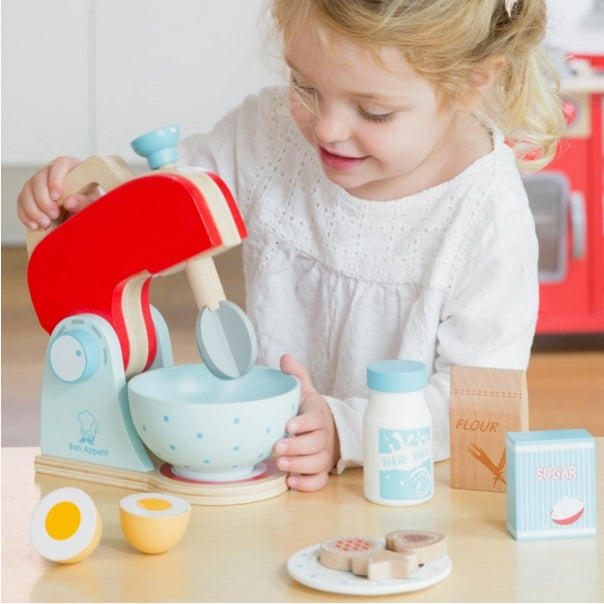 Child playing with a toy kitchen set on a wooden table