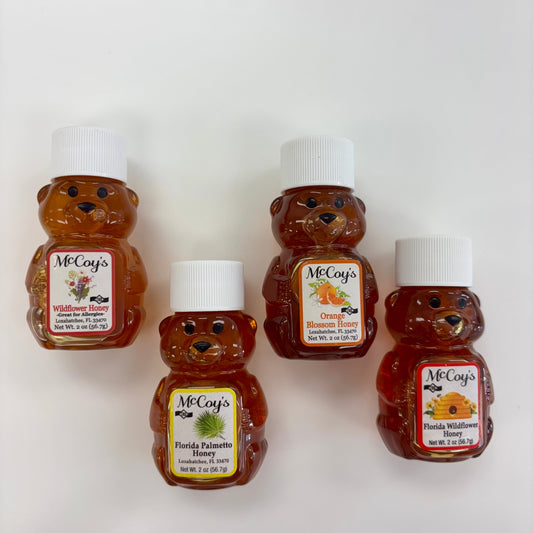 Five bear-shaped honey bottles with labels on a white background