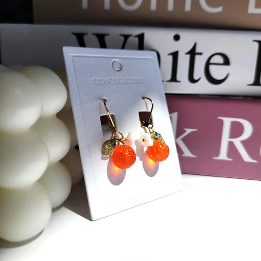 Pair of earrings on a display card with decorative items in the background