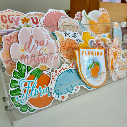 Collection of decorative stickers with Florida-themed designs on a clear stand.