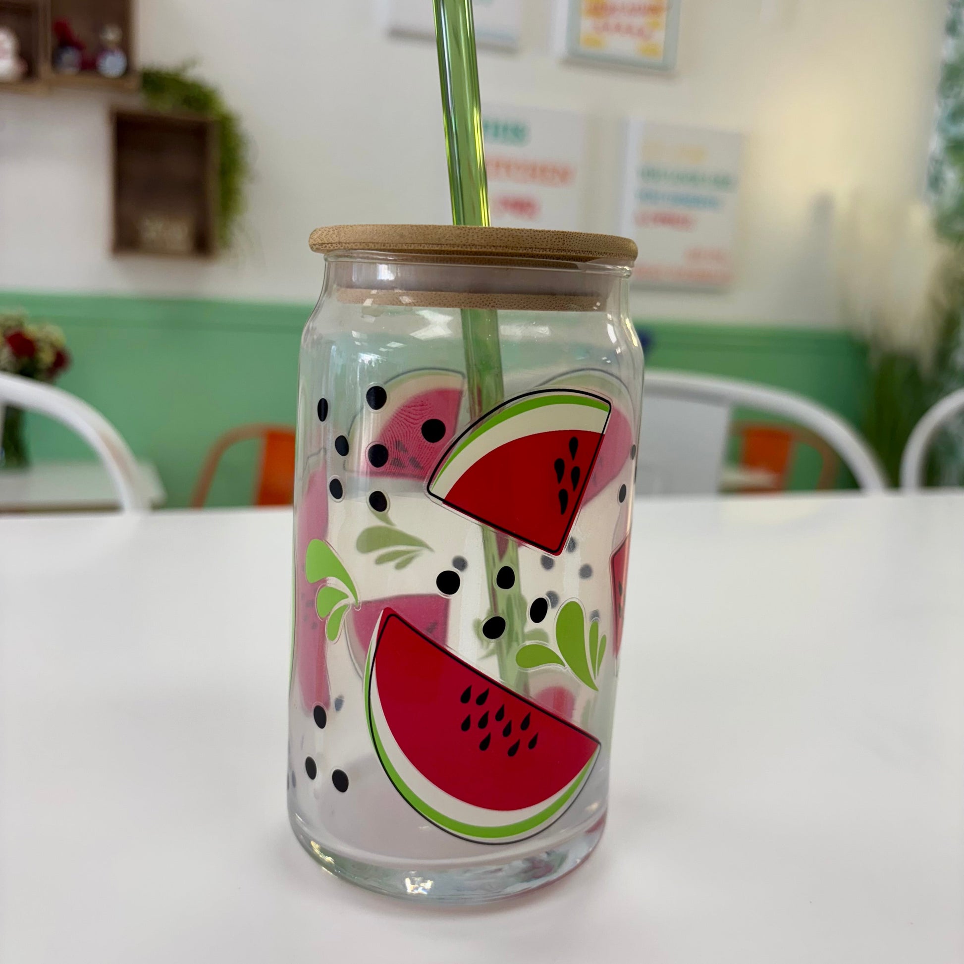 Glass tumbler with watermelon design and straw on a white surface